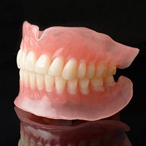 Full upper and lower dentures against dark background